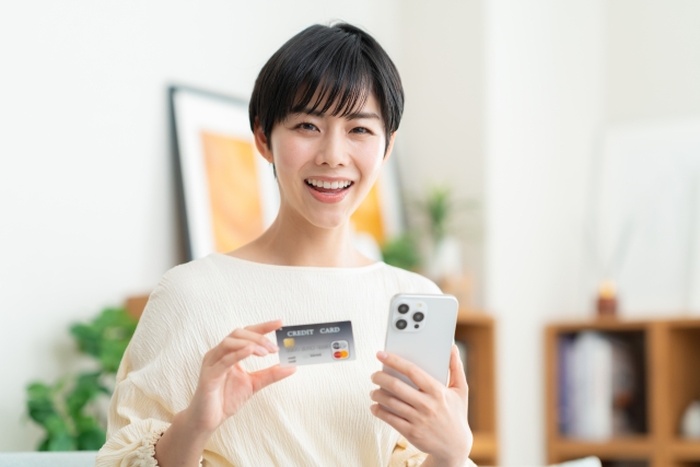 退職代行の決済をするためにクレジットカードを持った笑顔の女性の画像