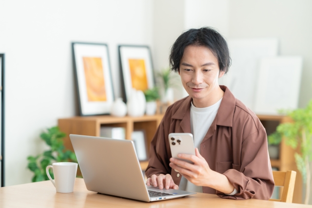退職代行は自宅にいながらにして退職ができるサービスということを伝えるための、自宅でスマホを見ている男性の画像